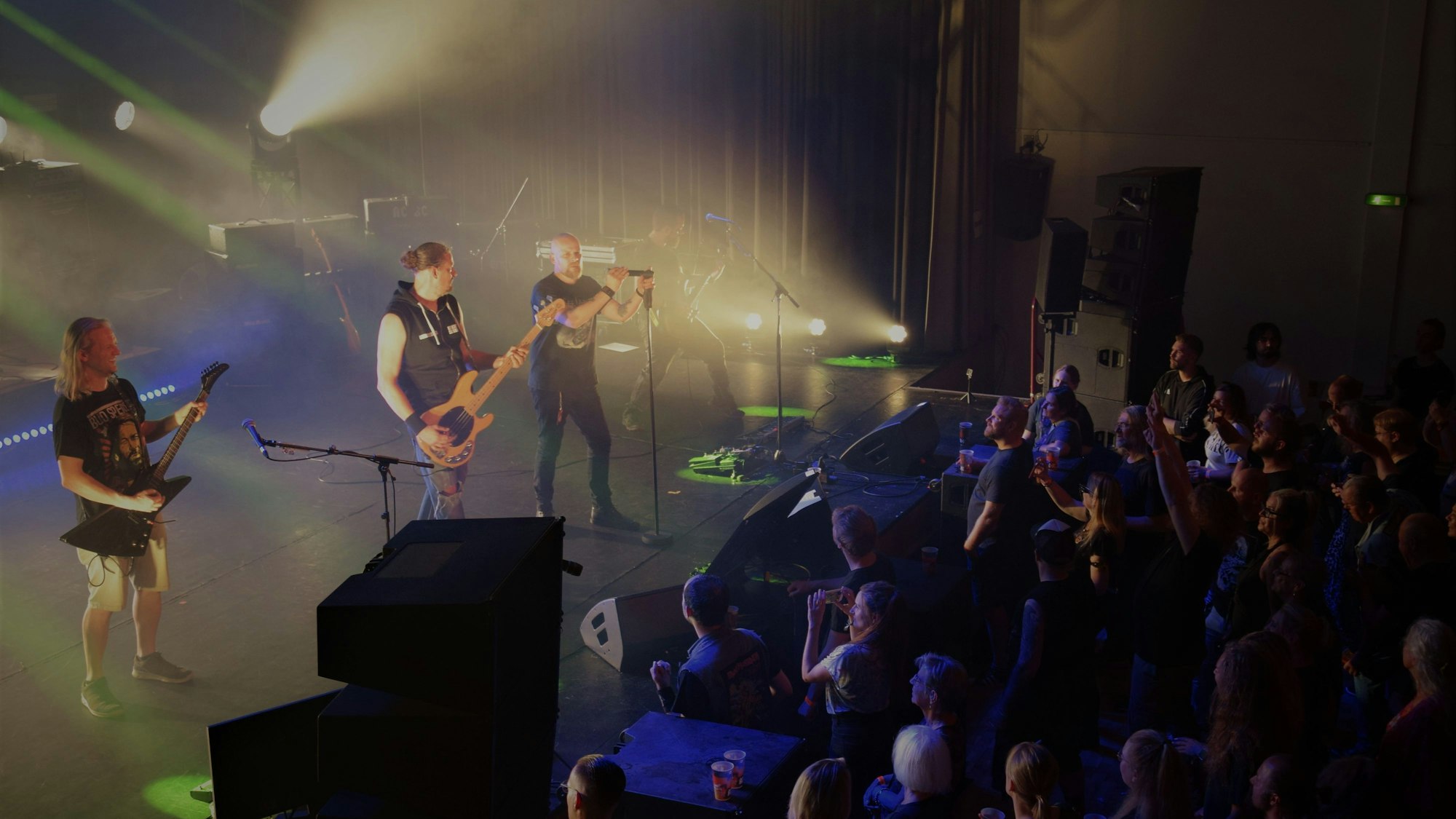 Das Foto zeigt eine Band, die Fans vor der Bühne jubeln.