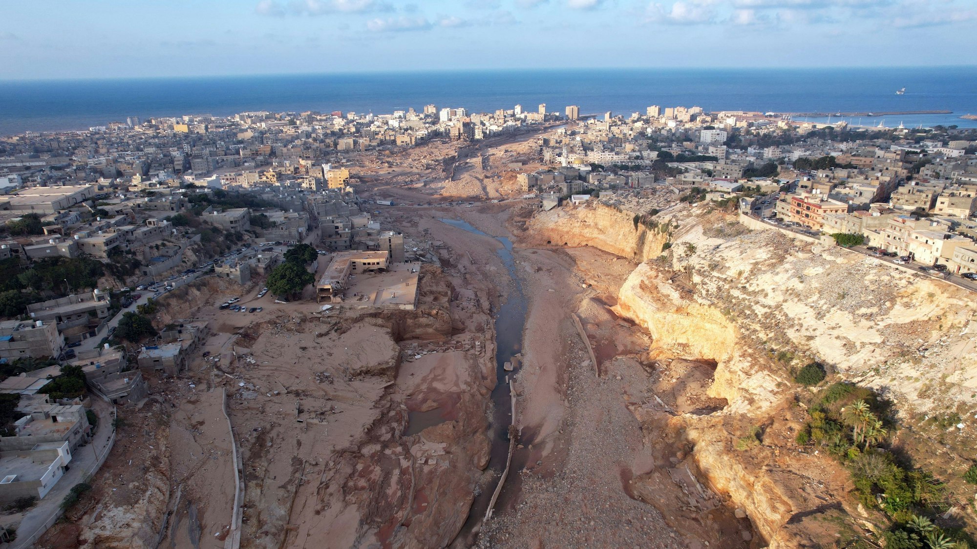 16.09.2023, Libyen, Darna: Diese Luftaufnahme zeigt ein von den Überschwemmungen betroffenes Gebiet in Derna, Libyen. Nach Angaben des UN-Nothilfebüros (OCHA) kamen allein in der stark zerstörten Hafenstadt Darna rund 11 300 Menschen ums Leben. Unterdessen wächst die Sorge vor möglichen gesundheitlichen Auswirkungen für die Bevölkerung der Stadt. Foto: Hamza Turkia/XinHua/dpa +++ dpa-Bildfunk +++