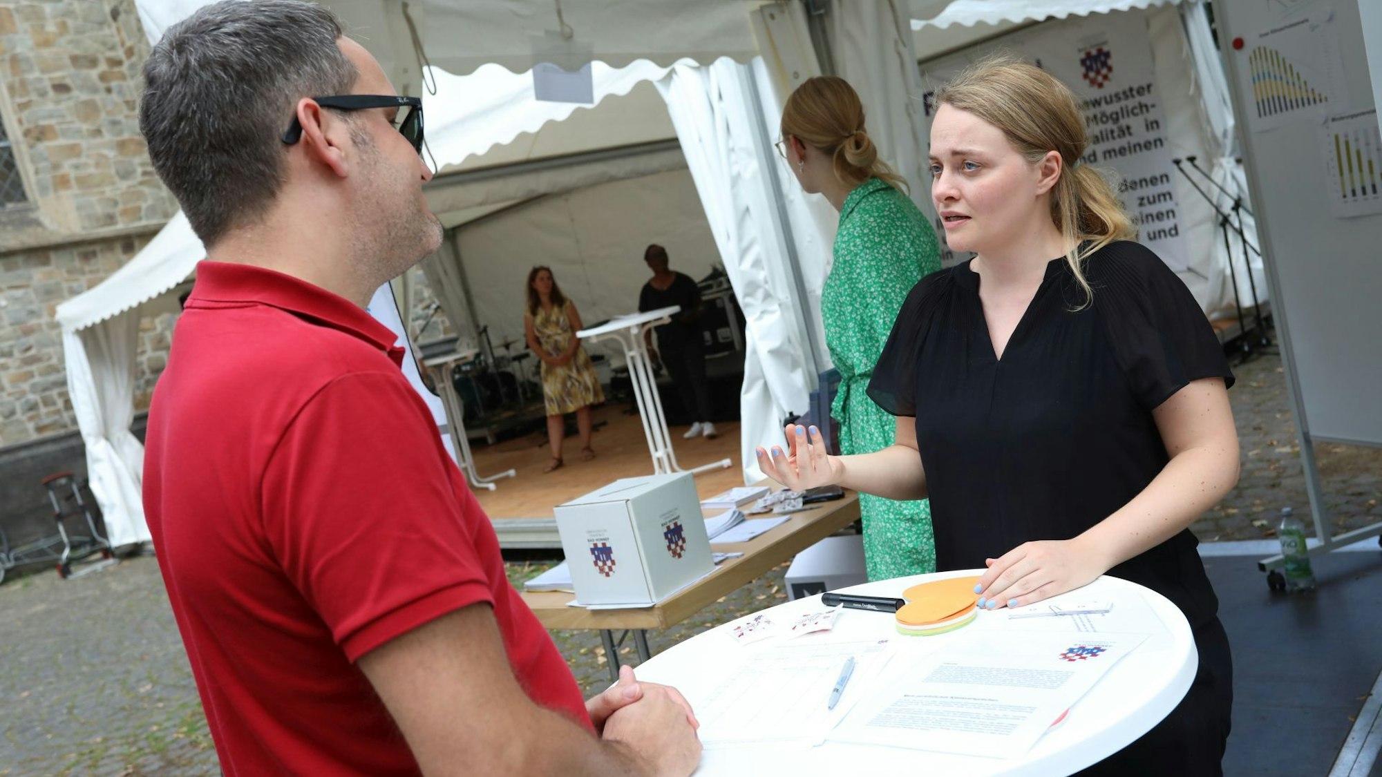 Ein Mann und eine Frau im angeregten Gespräch, vor ihnen auf einem Stehtisch liegt eine Liste.