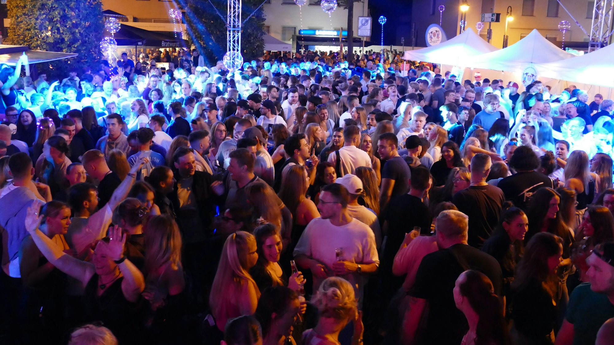 Eine Menge von jungen Menschen tanzt dicht an dicht auf einem Platz.