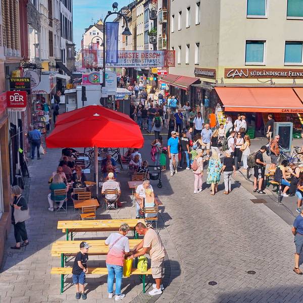 Blick auf die Severinstraße von oben, Menschen sitzen und gehen über die Straße.