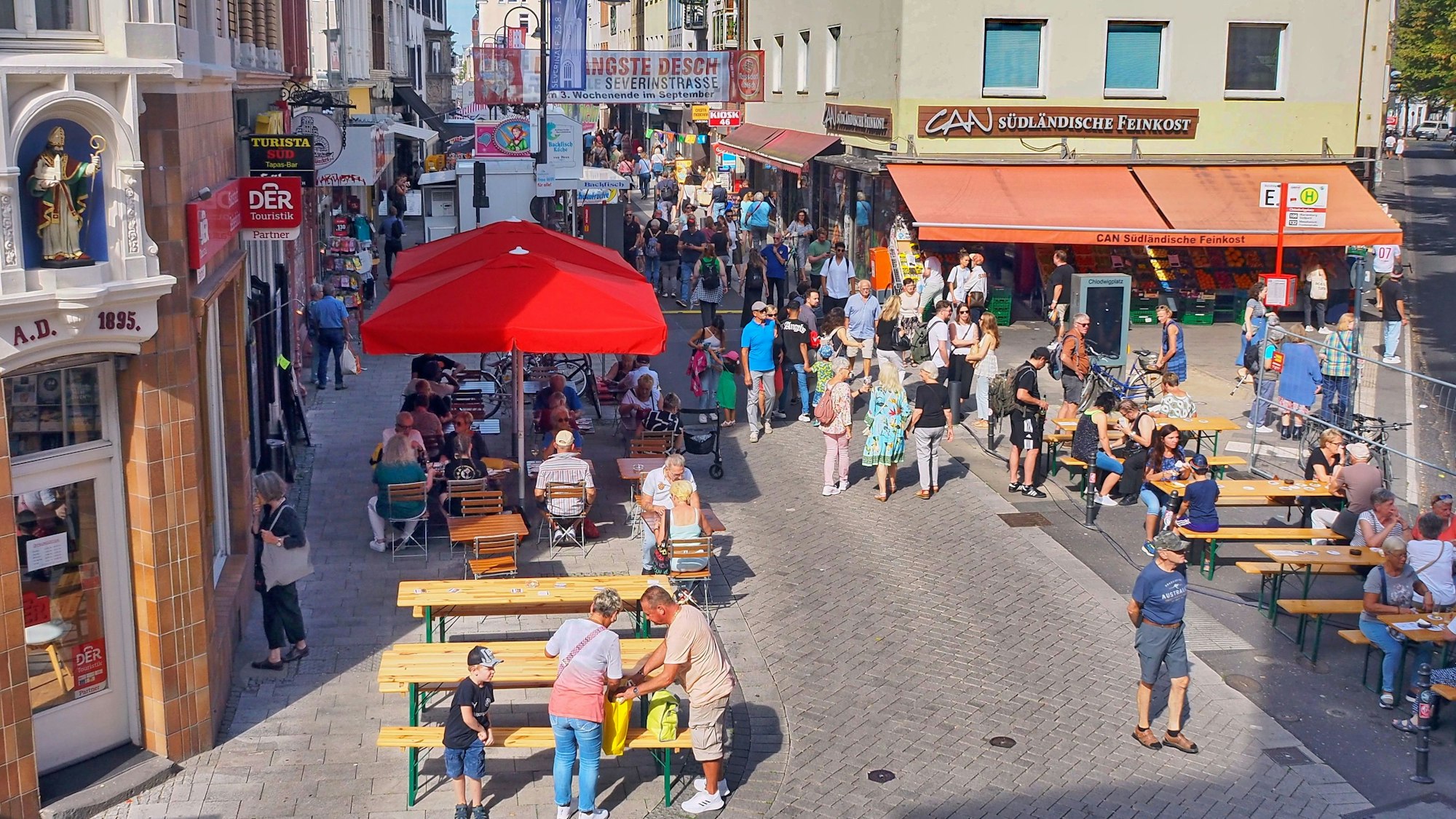 Blick auf die Severinstraße von oben, Menschen sitzen und gehen über die Straße.