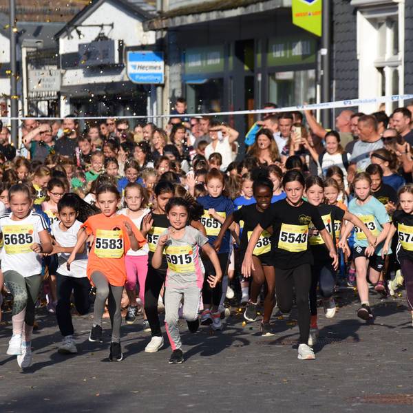 Zahlreiche Kinder starten unter Konfettiregen bei einem Stadtlauf an der Ziellinie.