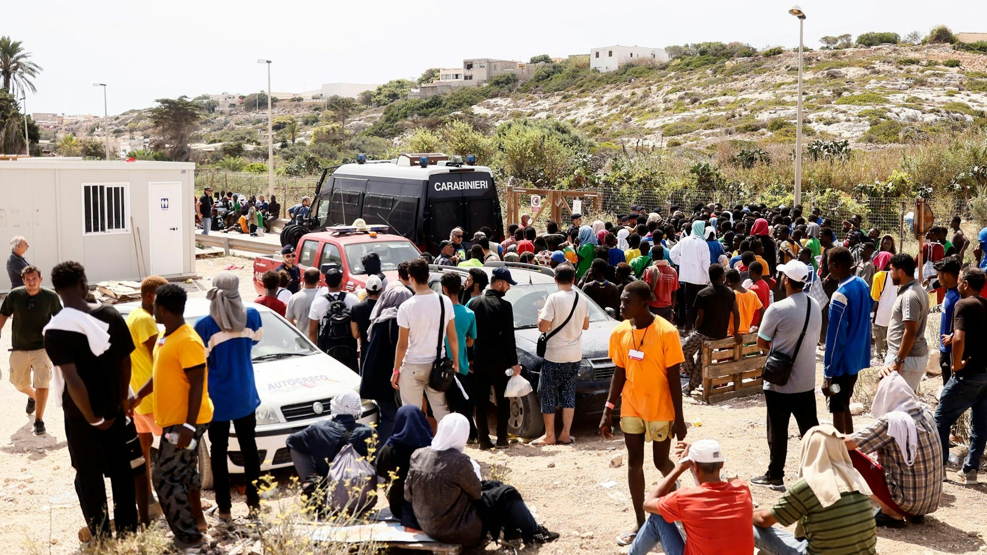 Geflüchtete vor einer Aufnahmestation auf Lampedusa, der italienischen Insel.
