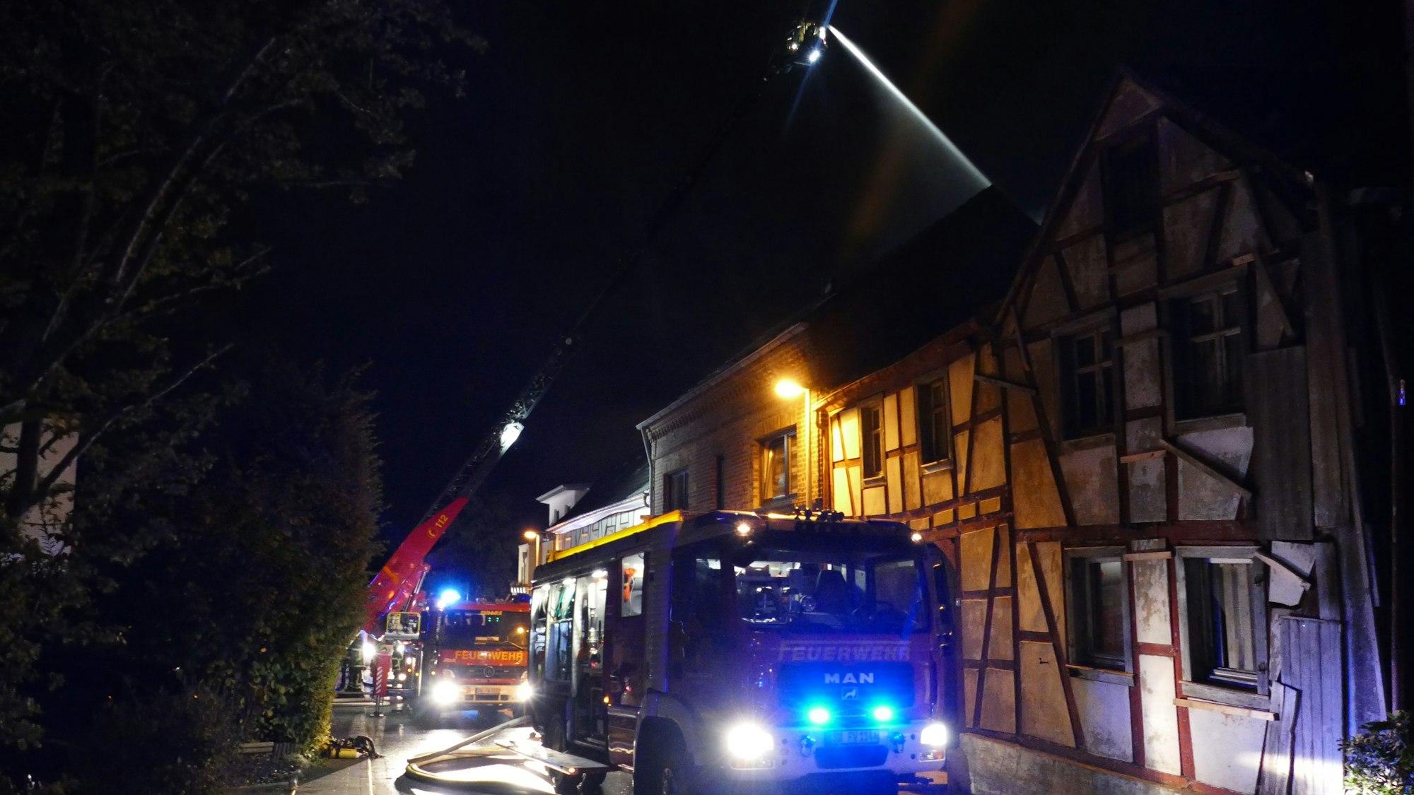 Feuerwehrfahrzeuge stehen vor einem Fachwerkhaus.