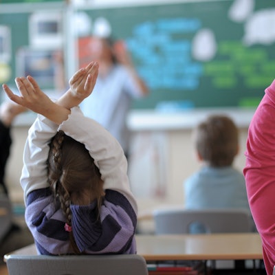 Zwei Schülerinnen melden sich während des Unterrichts in einem Klassenzimmer einer Grundschule.