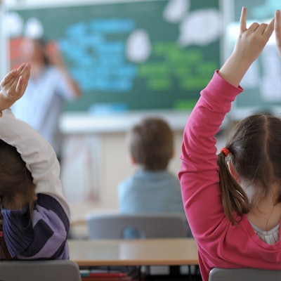Zwei Schülerinnen der vierten Klasse zeigen im Unterricht auf.