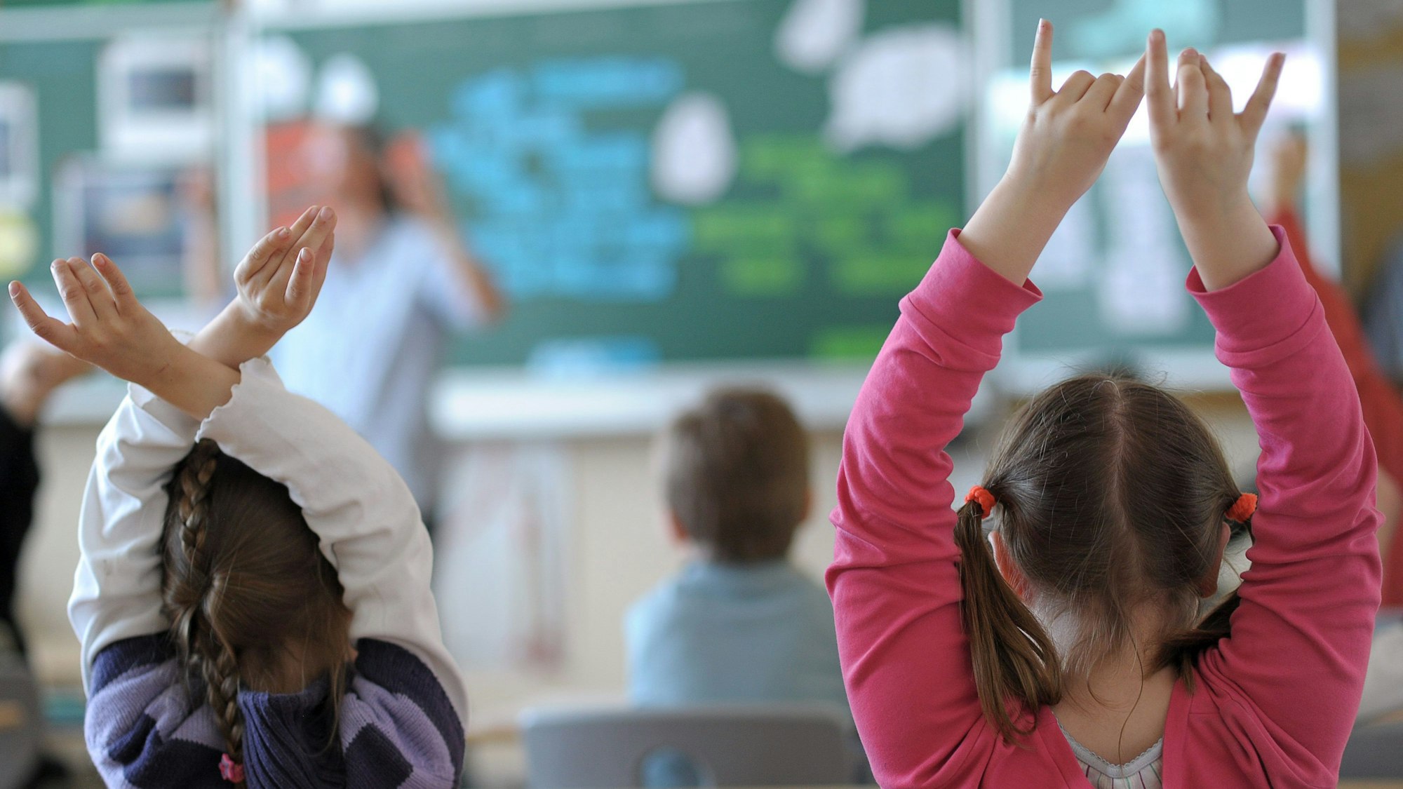 Zwei Schülerinnen der vierten Klasse zeigen im Unterricht auf.