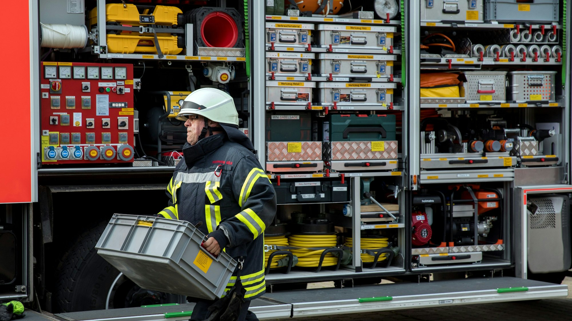 Ein Feuerwehrmann räumt einen Feuerwehrwagen ein.