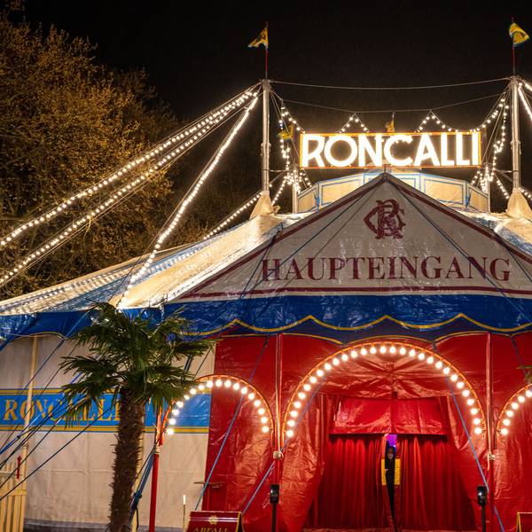 Das Roncalli-Zirkuszelt mit beleuchtetem Schriftzug am Abend ist zu sehen.