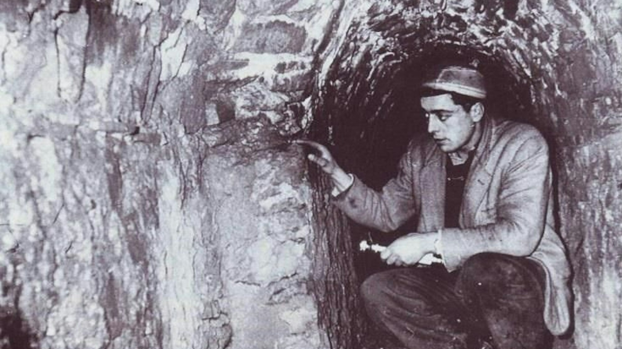 Ein Mann sitzt gehockt in einem gemauerten Kanal.