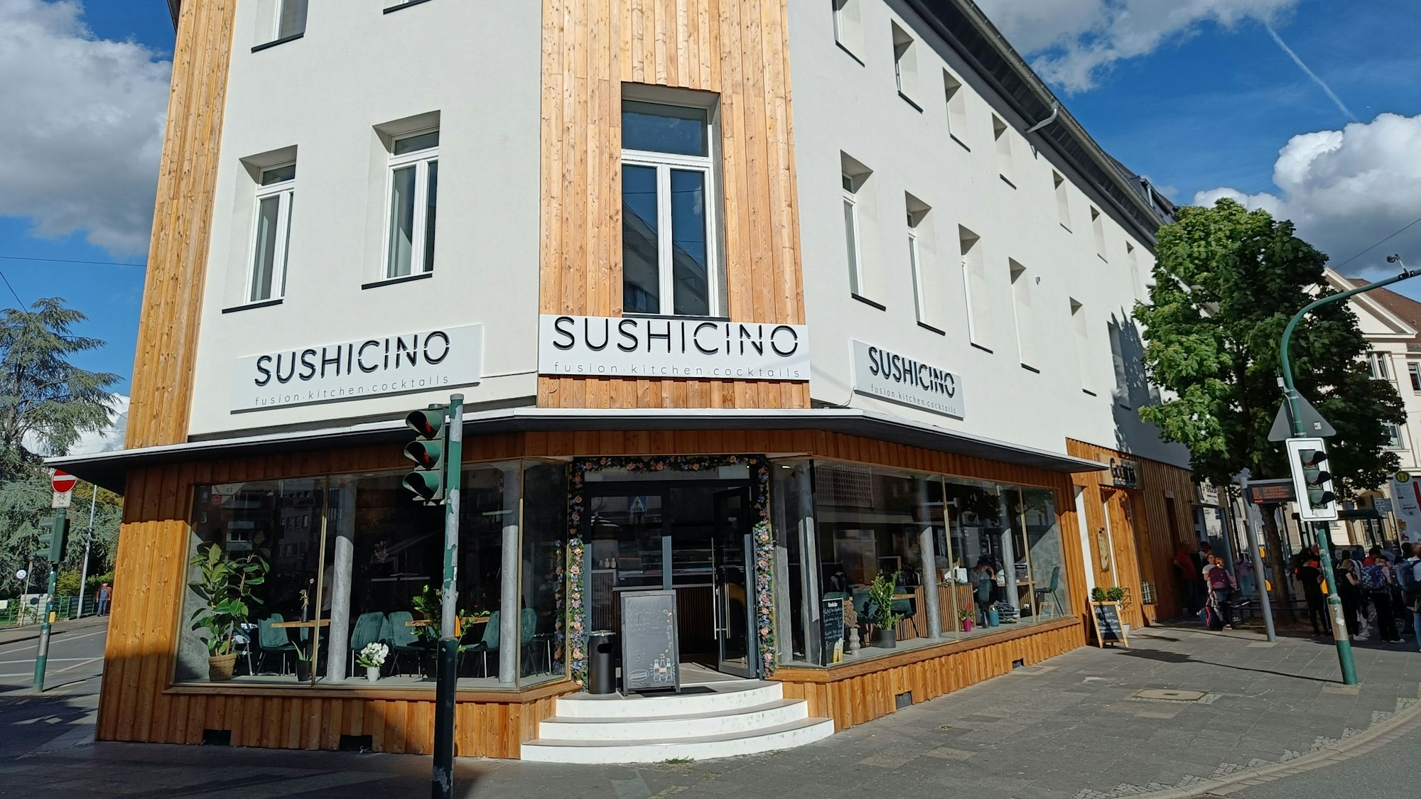 Ein weiß gestrichenes Gebäude an einer Straßenecke. Auf großen Schildern steht der Name des Lokals.