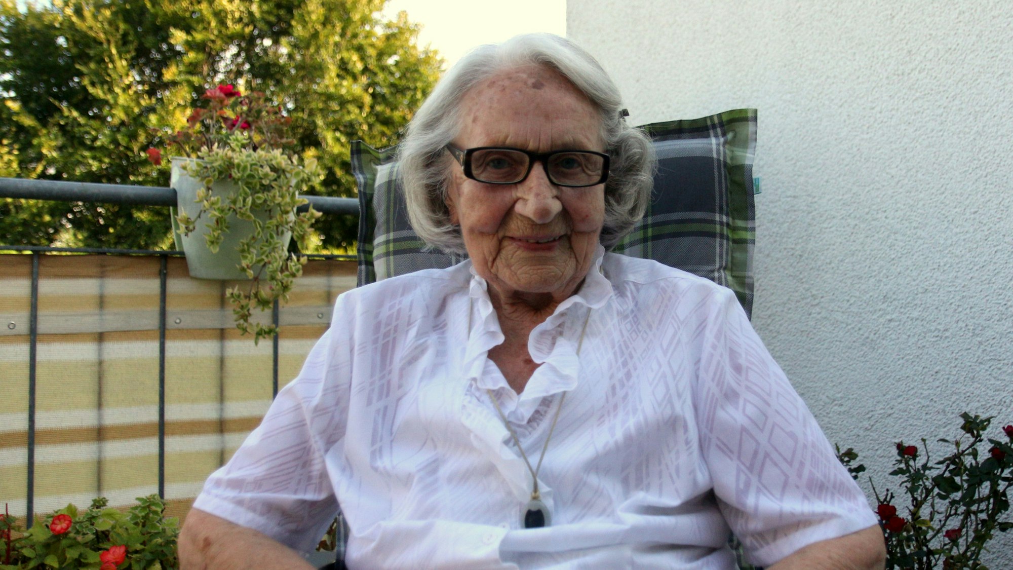 Die fröhlich lächelnde Jubilarin sitzt auf dem Balkon ihrer Wohnung.