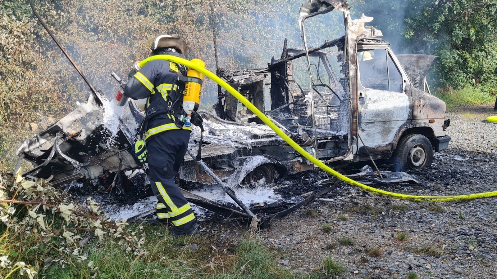 Ein Feuerwehrmann löscht ein brennendes Fahrzeug.
