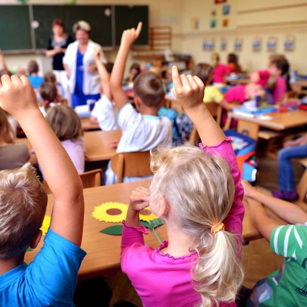 Kinder sitzen in einer vollen Schulklasse an ihren Pulten.