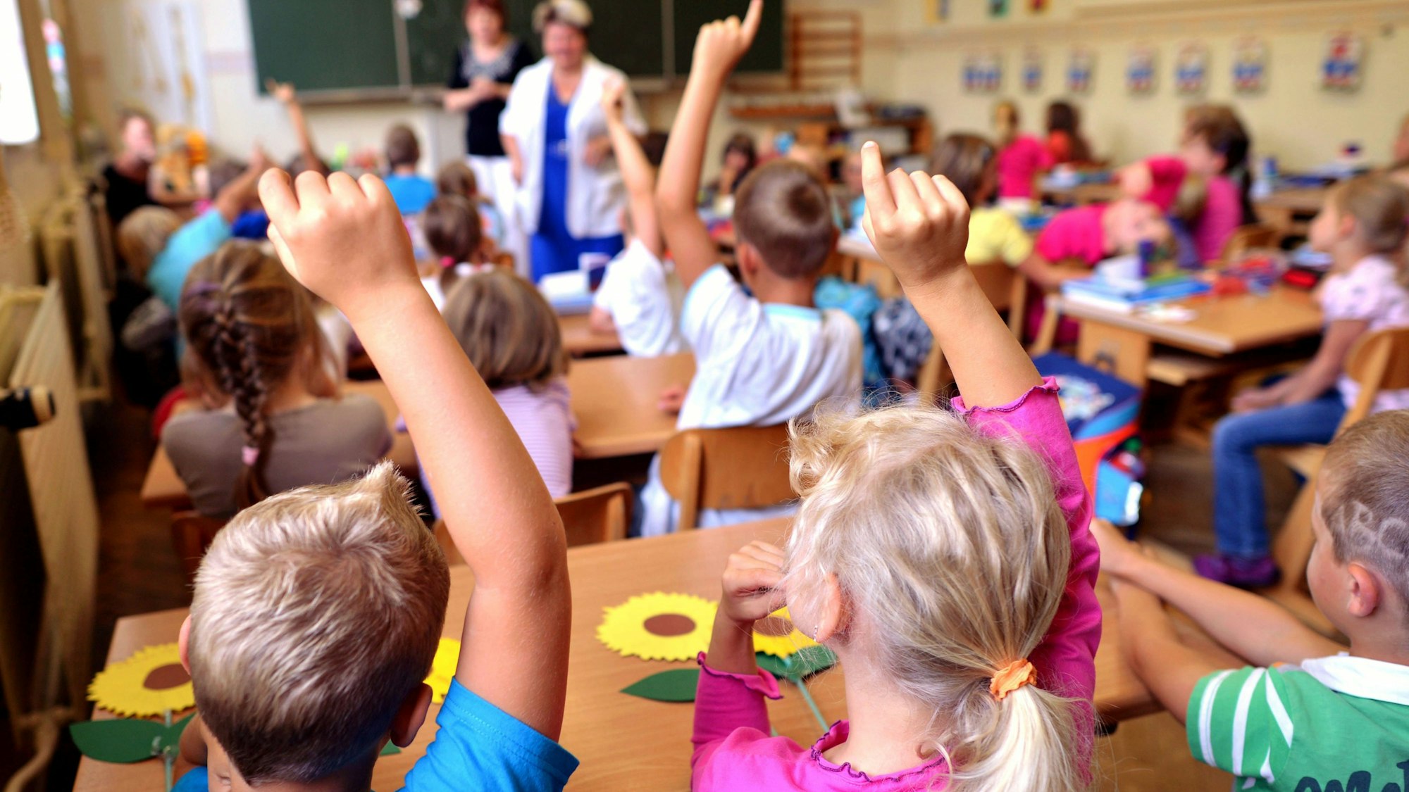 Kinder sitzen in einer vollen Schulklasse an ihren Pulten.