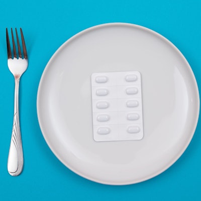 Tablettenpackung auf einem Teller mit Messer und Gabel daneben