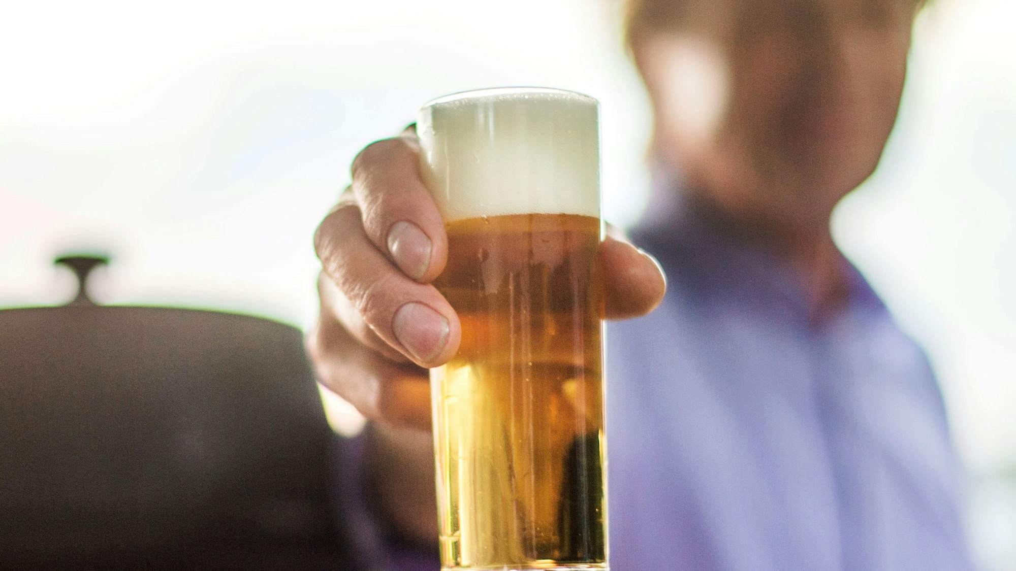 Ein frisch gezapftes Kölsch wird auf einer Party in die Kamera gehalten.