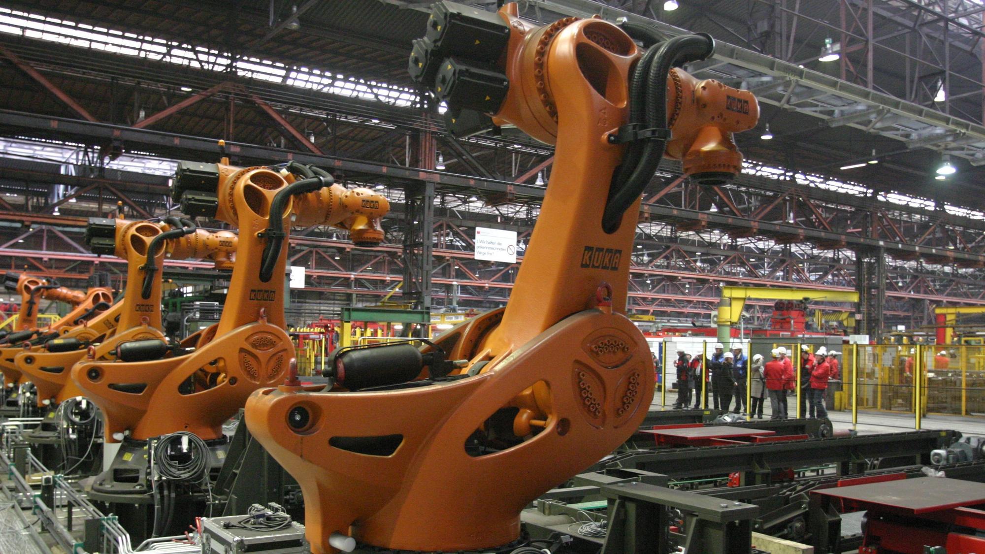 Fünf orangerote Roboter in einer Fabrikhalle von Mannstaedt