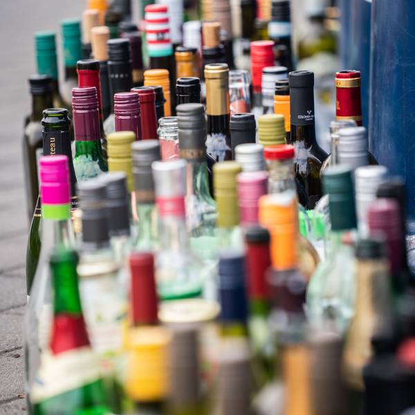 Zahlreiche leere Flaschen stehen vor einem bereits überfüllten Flaschencontainer.