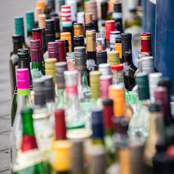 Zahlreiche leere Flaschen stehen vor einem bereits überfüllten Flaschencontainer.