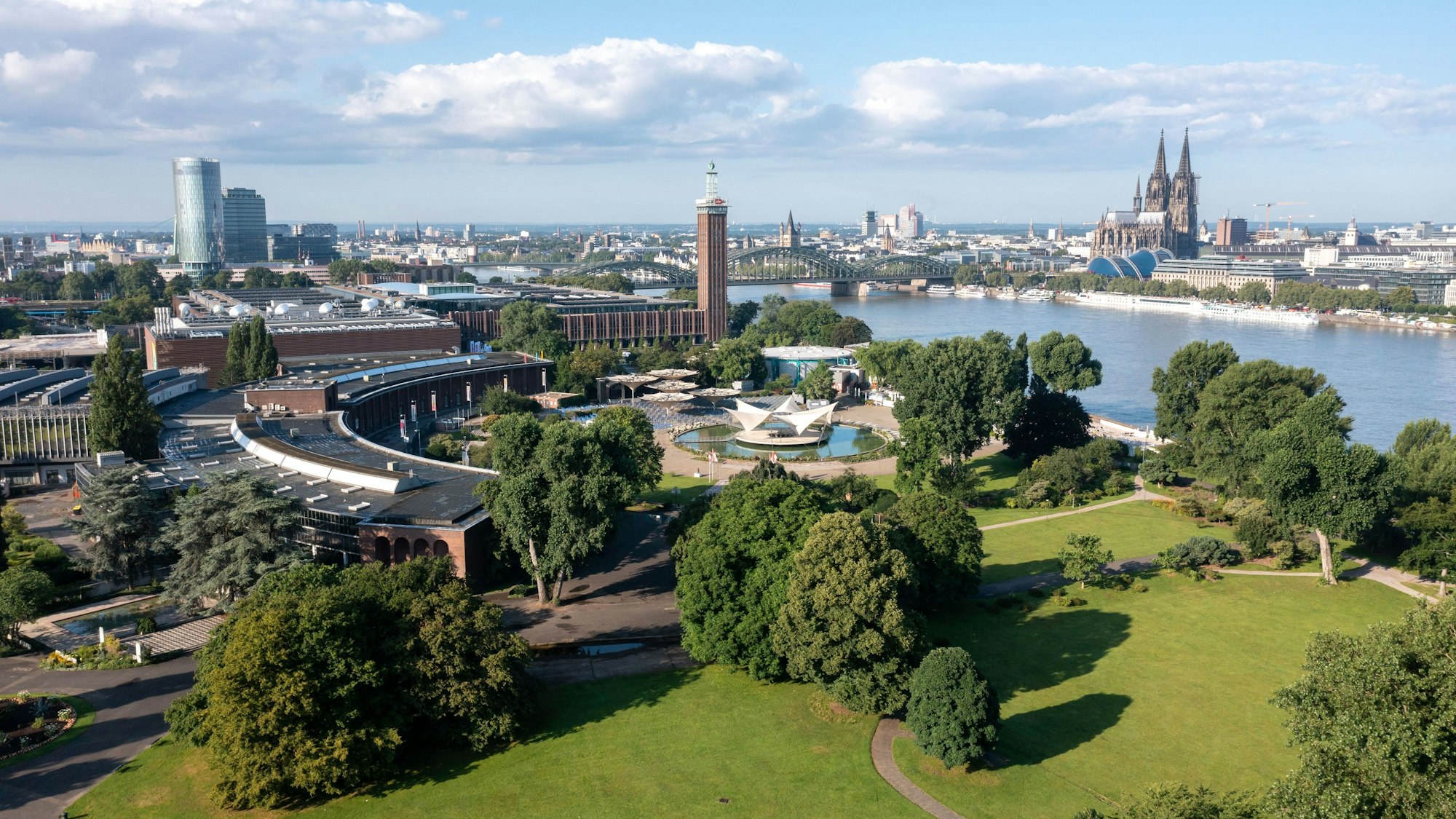 Das Bild zeigt den Rheinpark mit dem Tanzbrunnen und den alten Messehallen aus der Vogelperspektive.