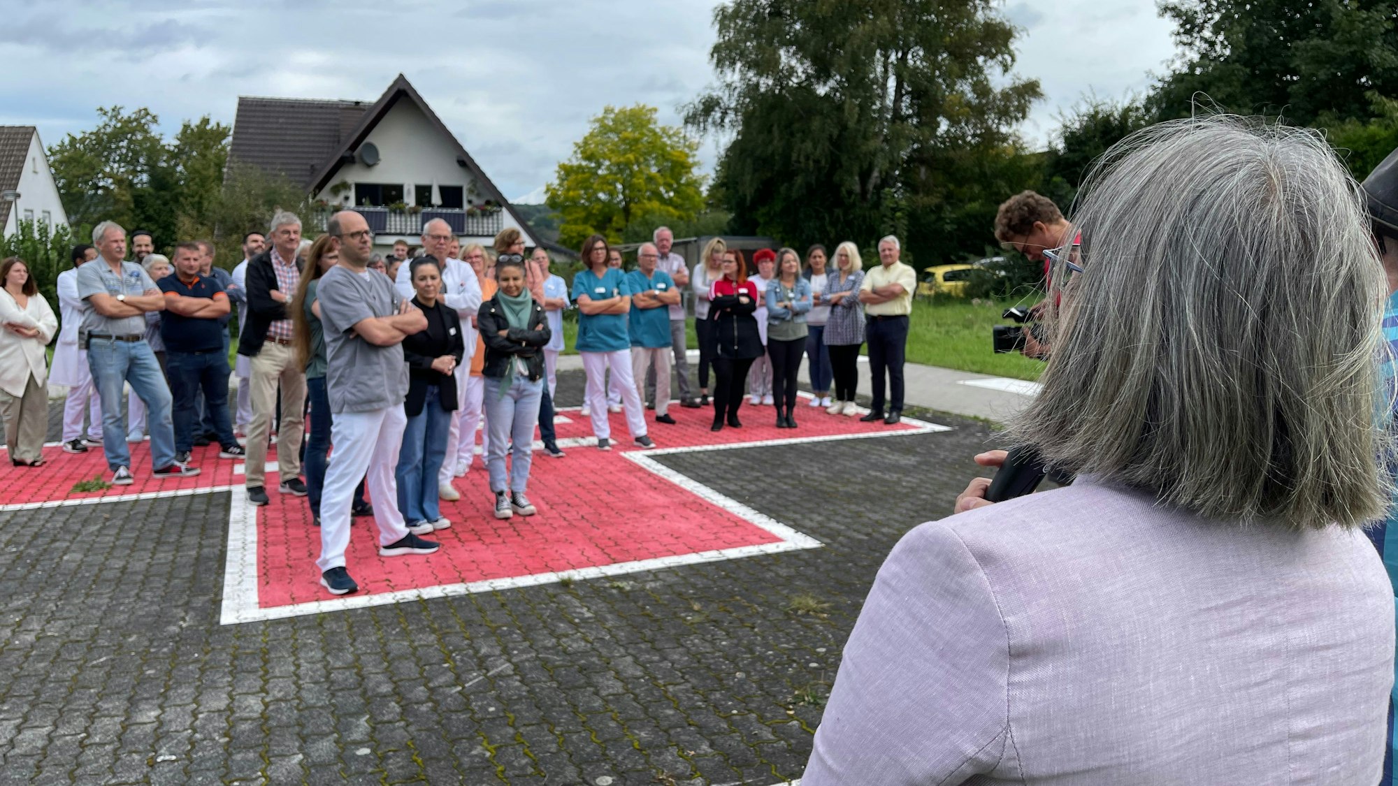 Eine Frau mit grauen Haaren steht am Mikrofon und spricht zu den Demonstranten.