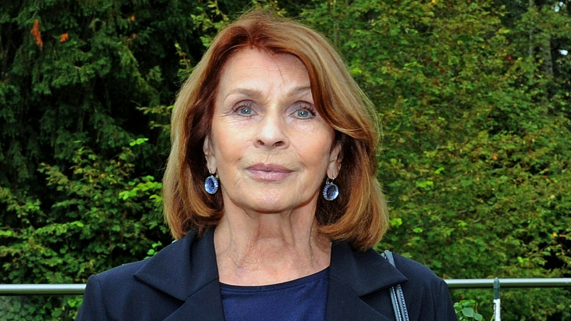 Die Schauspielerin Senta Berger lächelt im Rosengarten der Politischen Akademie am Starnberger See.