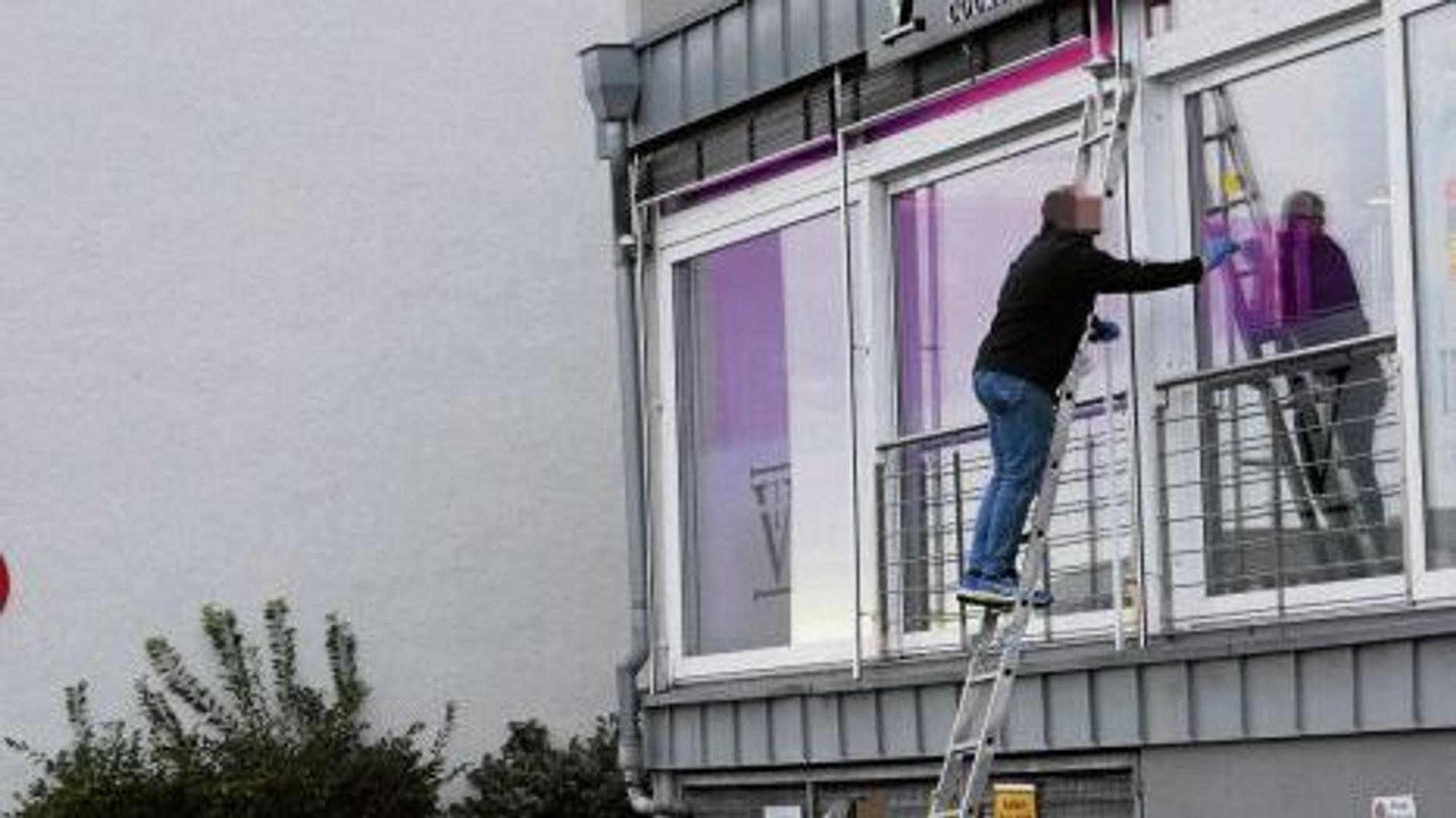 Spurensicherer der Polizei stehen auf einer Leider und sichern Spuren an Einschusslöchern in einer Glasfassade.