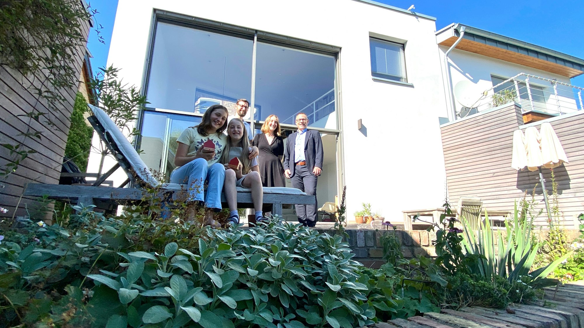 Drei Erwachsene und zwei Kinder stehen vor dem Anbau.