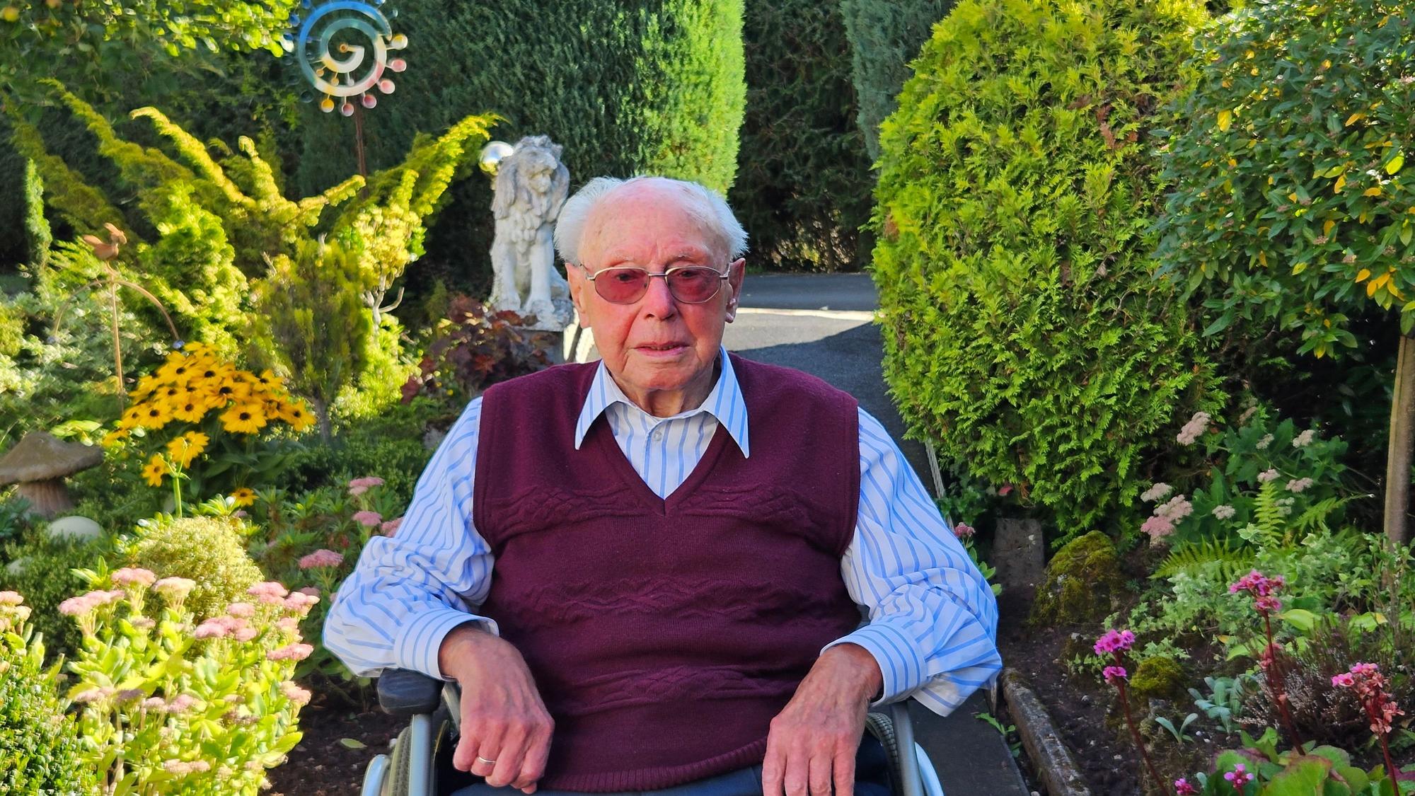 Emil Feyen sitzt in seinem Rollstuhl im Garten.