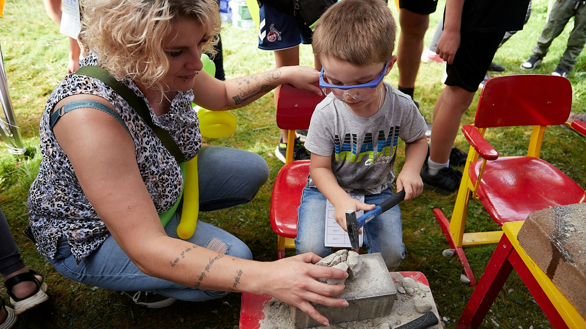 Ein kleiner Junge schlägt mit einem Hammer auf einen Zementbrocken, in dem ein Spielzeug versteckt ist.