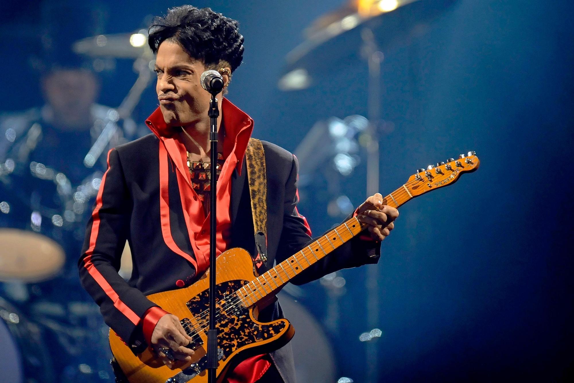 Prince steht auf einer Bühne und spielt Gitarre