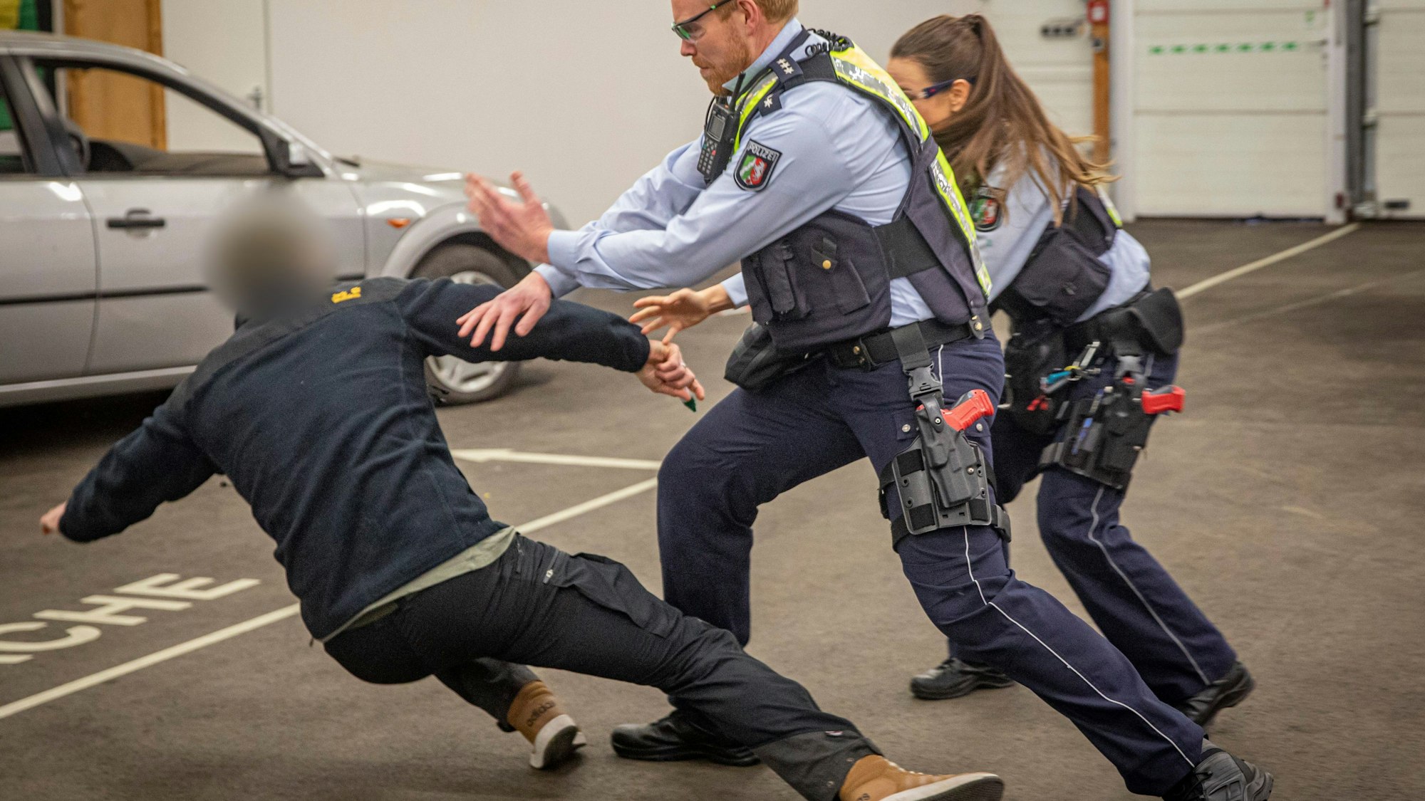 Polizeiübung: Ein unbekannter Mann greift zwei Uniformierte bei einer Standard-Kontrolle mit einer Stichwaffe an. Zwei Beamte wehren einen Angriff ab, der Statist geht zu Boden.