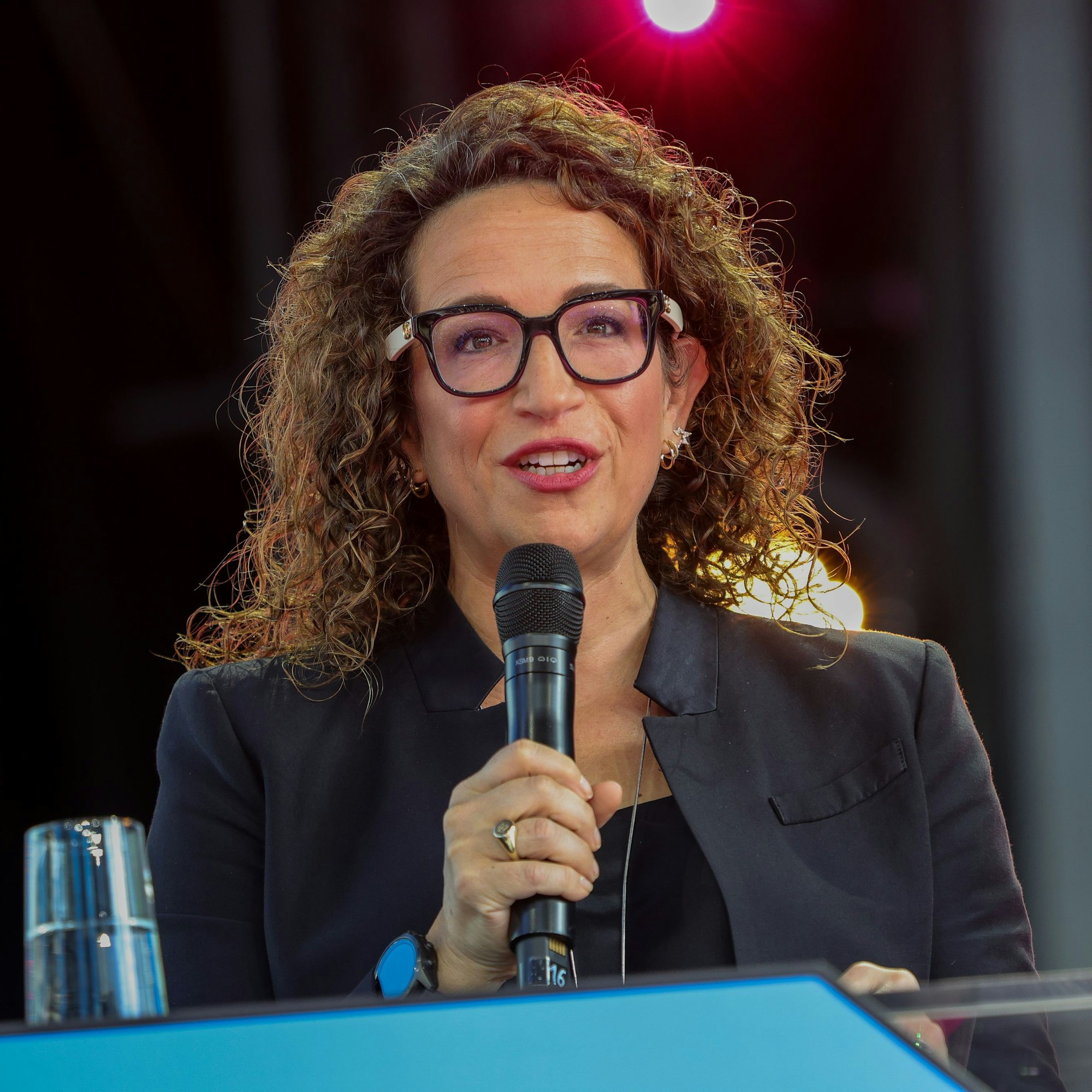 Eine Frau steht auf der Bühne und spricht in ein Mikrofon.
