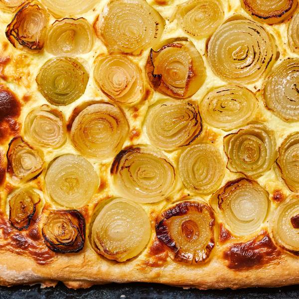 Zwiebelkuchen liegt auf einem Backblech.