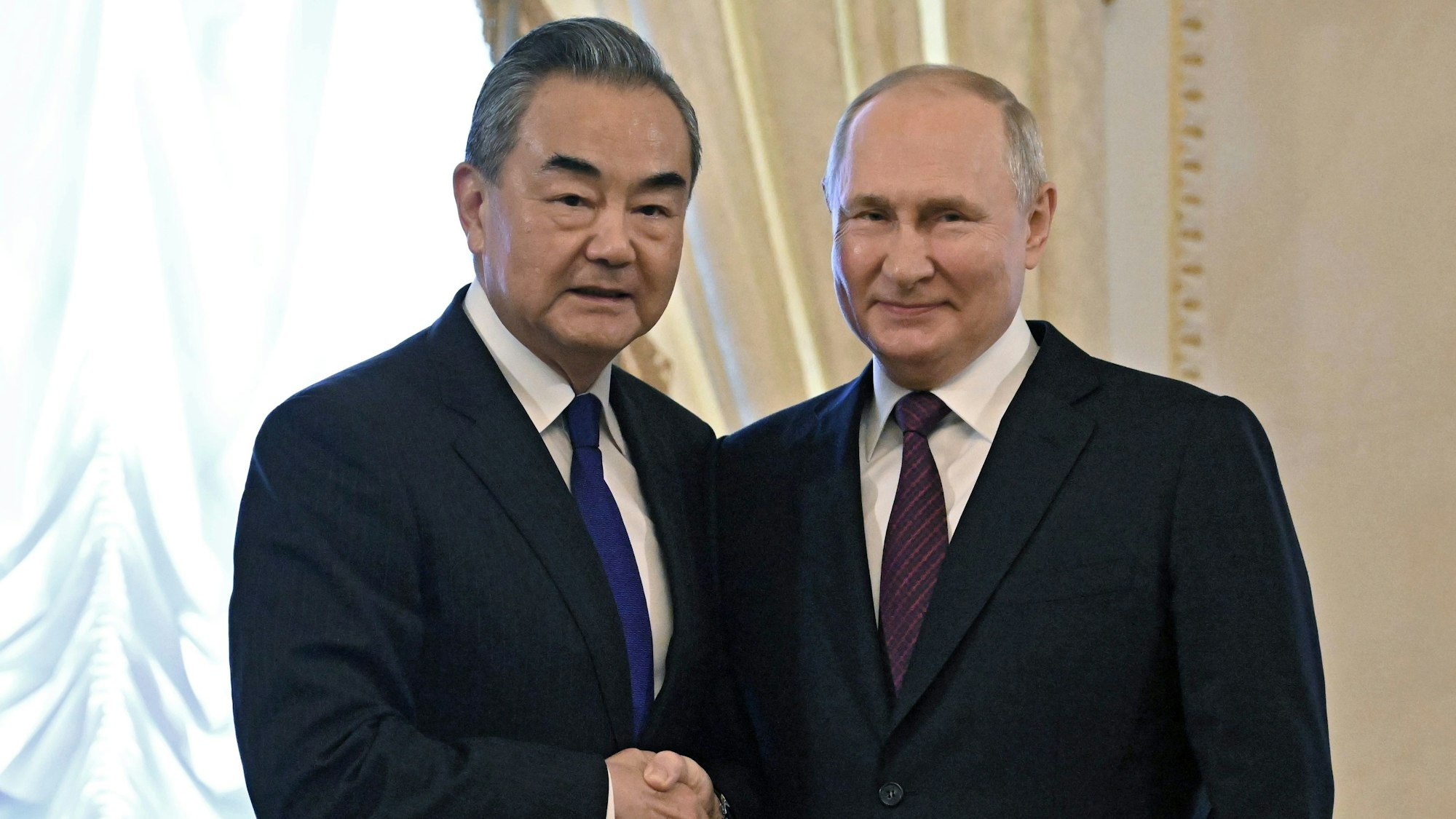 Wladimir Putin (r), der Präsident von Russland schüttelt Wang Yi, Außenminister von China, die Hand.