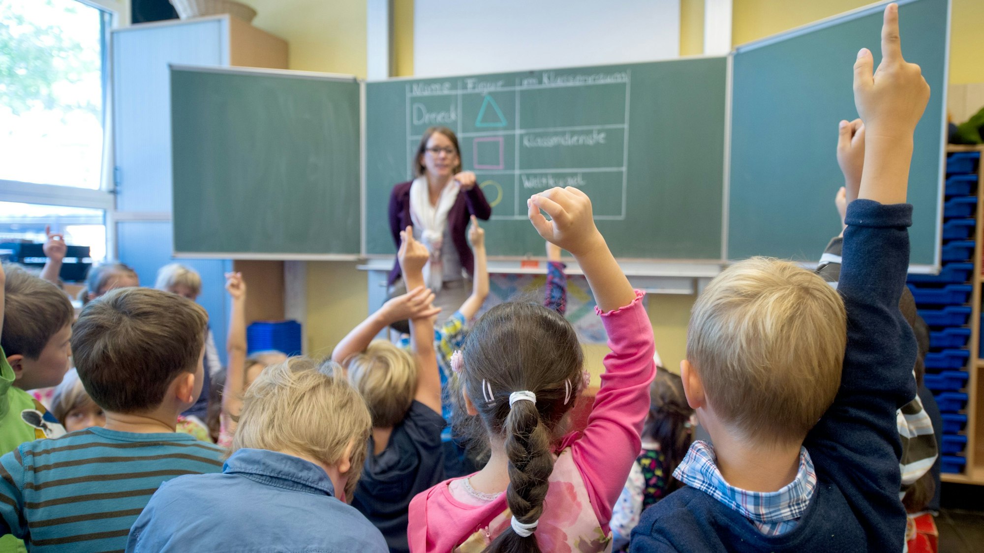 Erstklässler der 1A melden sich am 20.08.2014 während ihrer ersten Unterrichtsstunde in der Henri-Dunant-Schule in Düsseldorf (Nordrhein-Westfalen). Vorne steht ihre Klassenlehrerin Melanie Beaucamp.