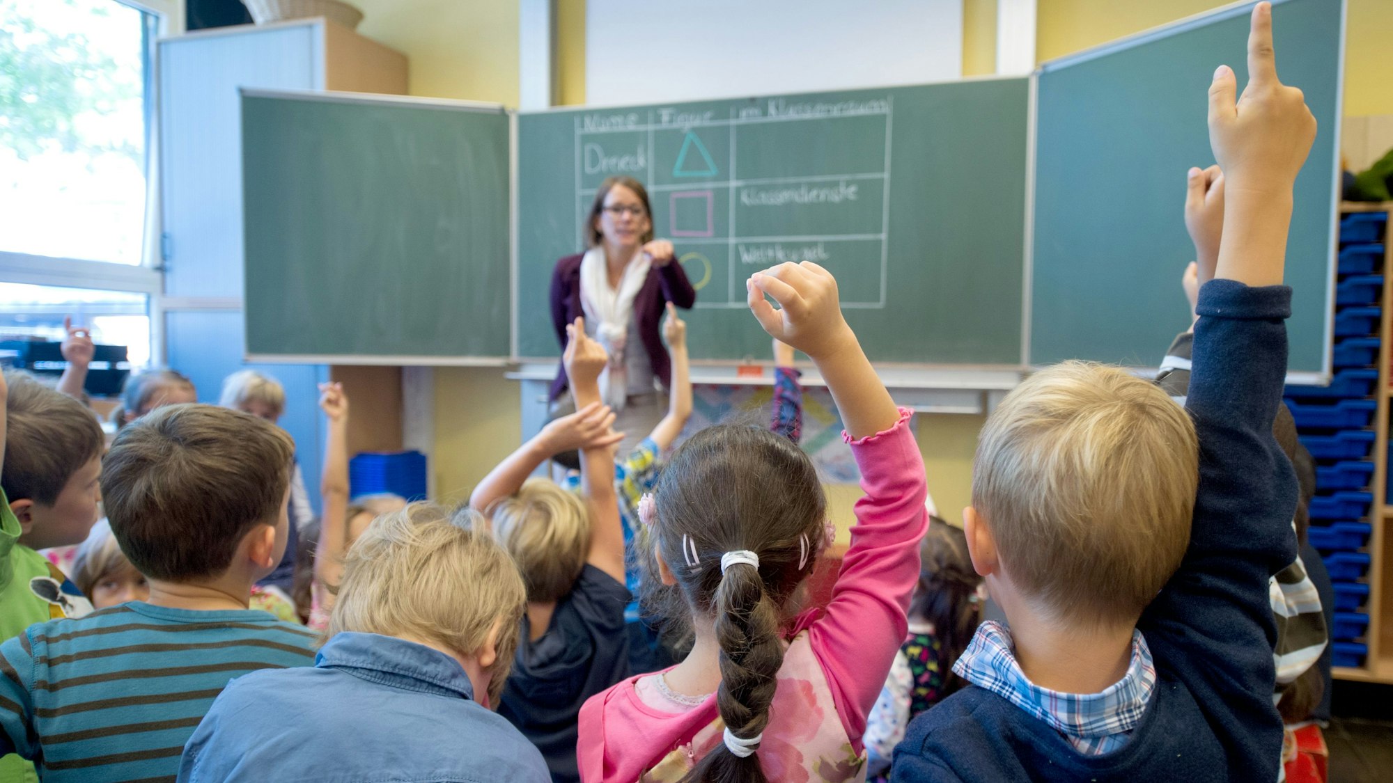 Eine Grundschullehrerin steht vor ihrer Klasse.