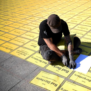 Ein Mann klebt Ortseingangsschilder auf den Gehweg (Archivfoto).
