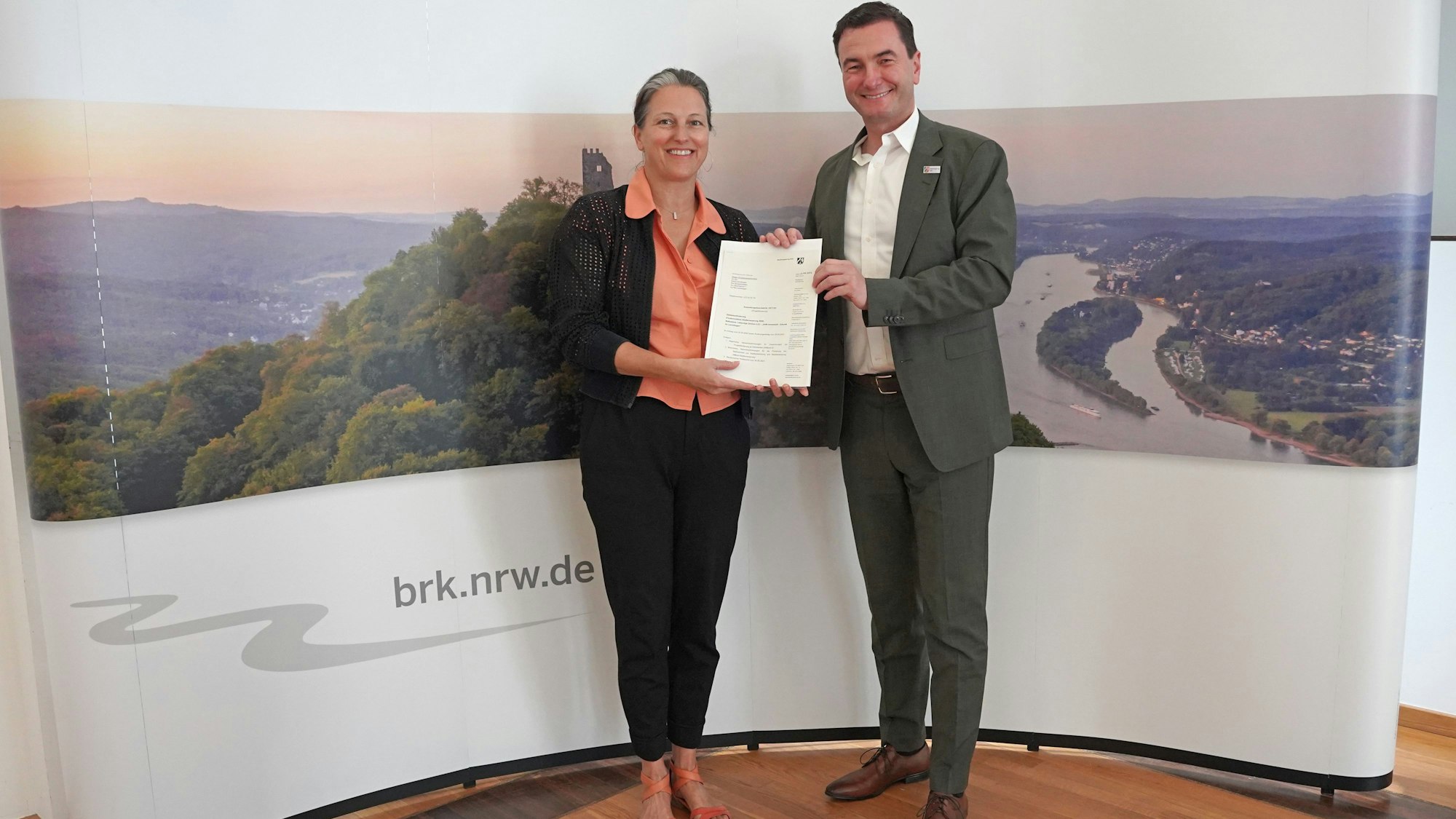 Fachbereichsleiterin Mirjam Bosse nimmt den Förderbescheid von Thomas Wilk, Regierungspräsident der Bezirksregierung Köln, entgegen.