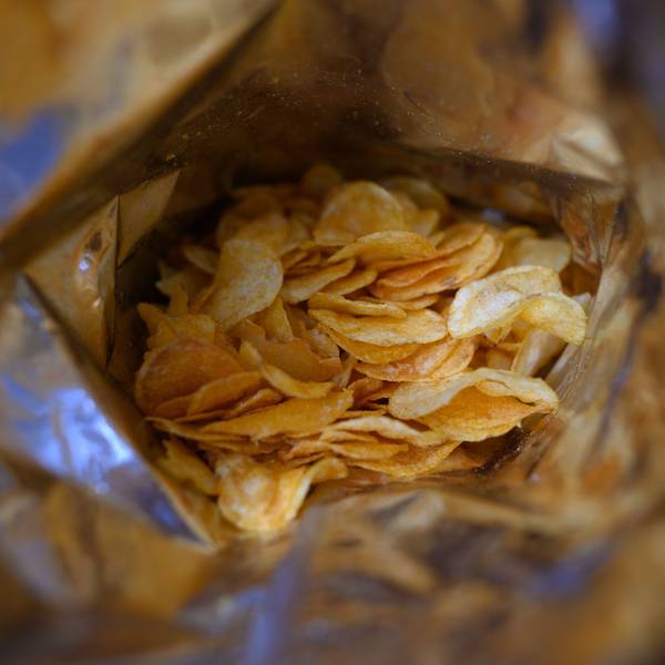 Eine offene Tüte Kartoffelchips liegt auf einem Tisch.