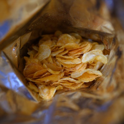 Eine offene Tüte Kartoffelchips liegt auf einem Tisch.