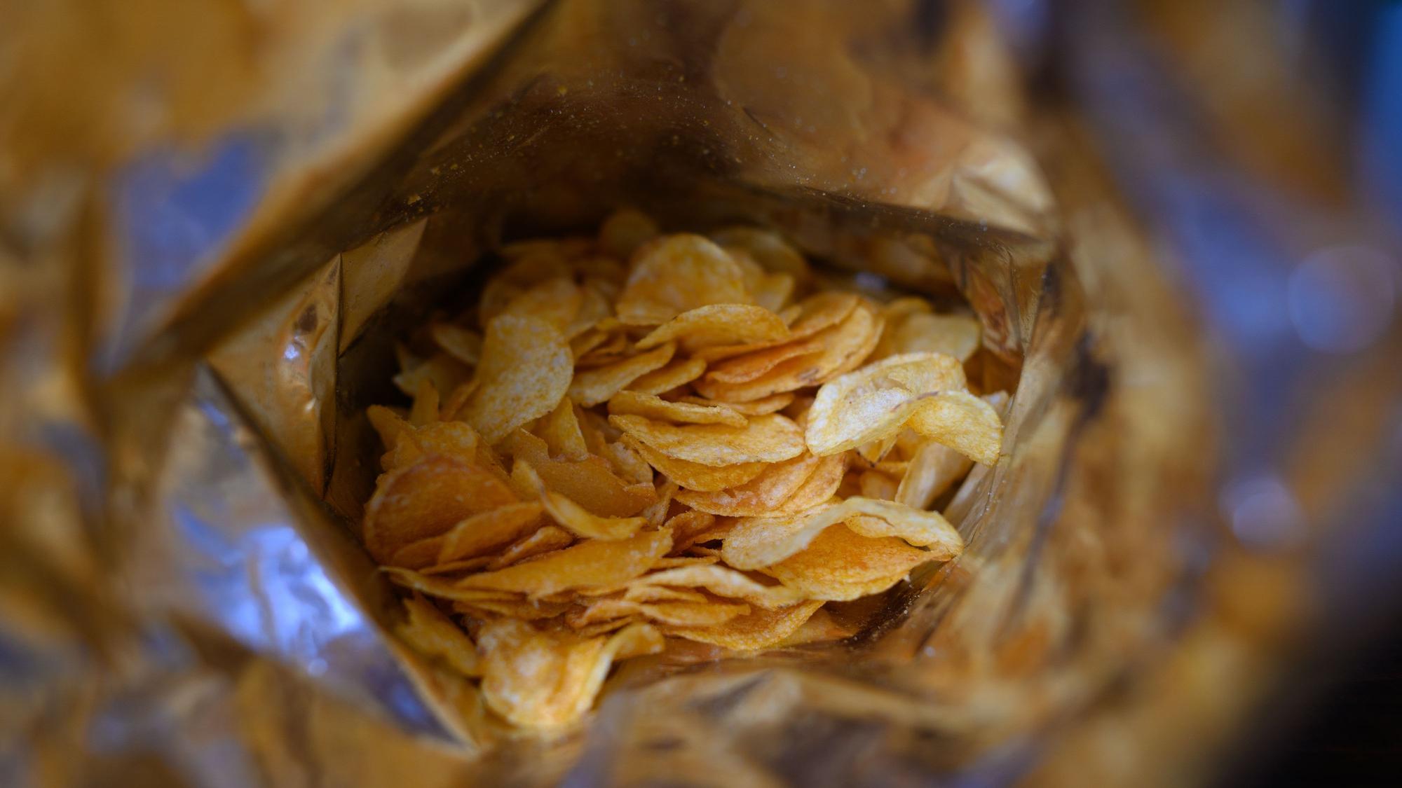 Eine offene Tüte Kartoffelchips liegt auf einem Tisch.
