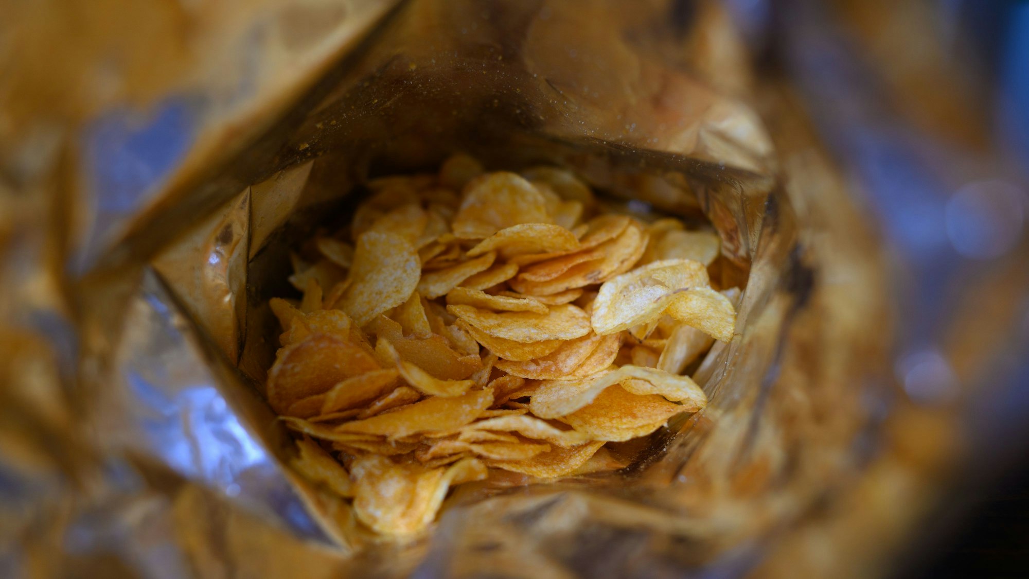 Eine offene Tüte Kartoffelchips liegt auf einem Tisch.