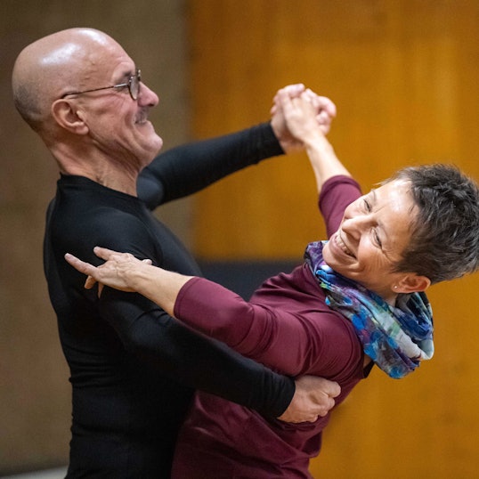 Ein Tanzpaar hält sich in de Armen, beide lachen.