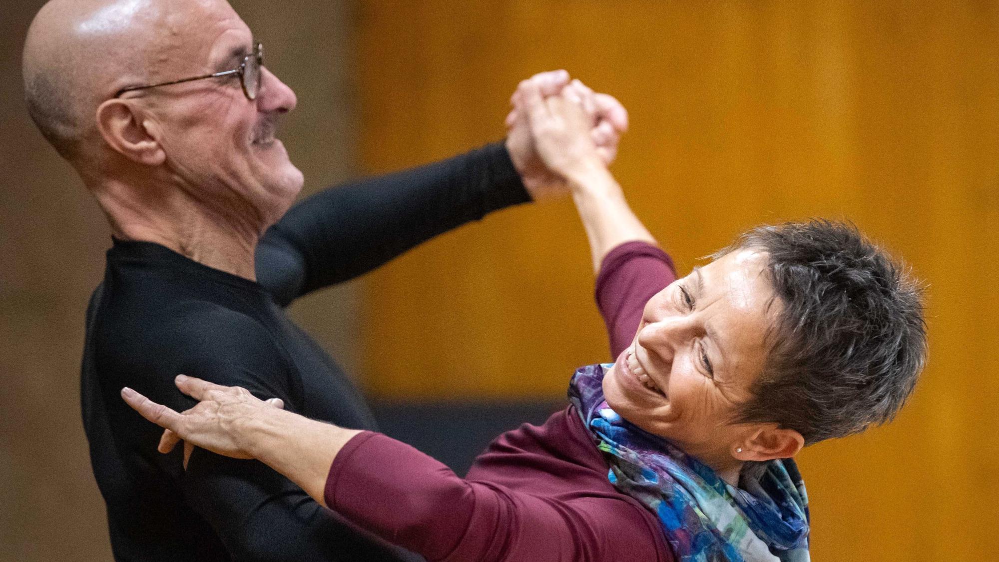 Ein Tanzpaar hält sich in de Armen, beide lachen.