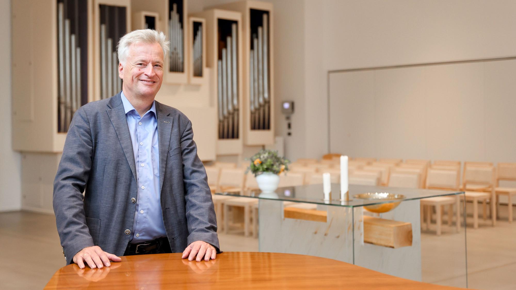 Ansichten der neuen evangelischen Erlöserkirche in Köln Weidenpesch. Pfarrer Markus Zimmermann ist vor dem gläsernen Altar in einem lichten Raum zu sehen.