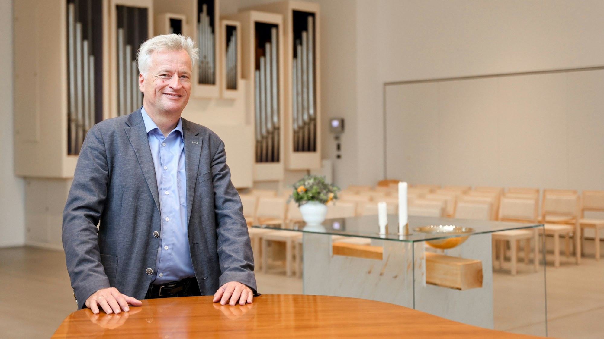 Ansichten der neuen evangelischen Erlöserkirche in Köln Weidenpesch. Pfarrer Markus Zimmermann ist vor dem gläsernen Altar in einem lichten Raum zu sehen.