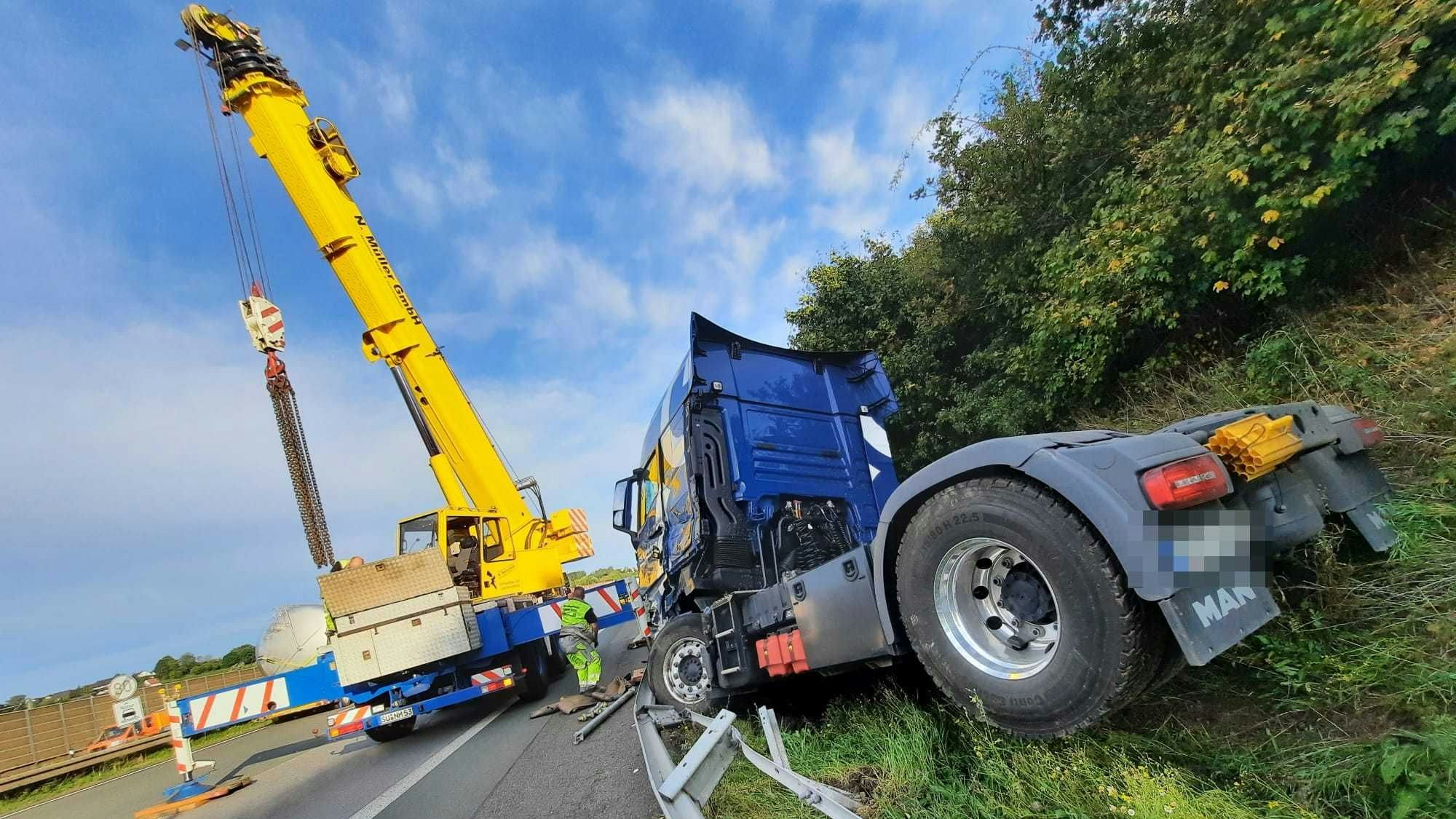 Die blaue Zugmaschine eines Sattelschleppers steht in der Böschung hinter der Leitplanke.